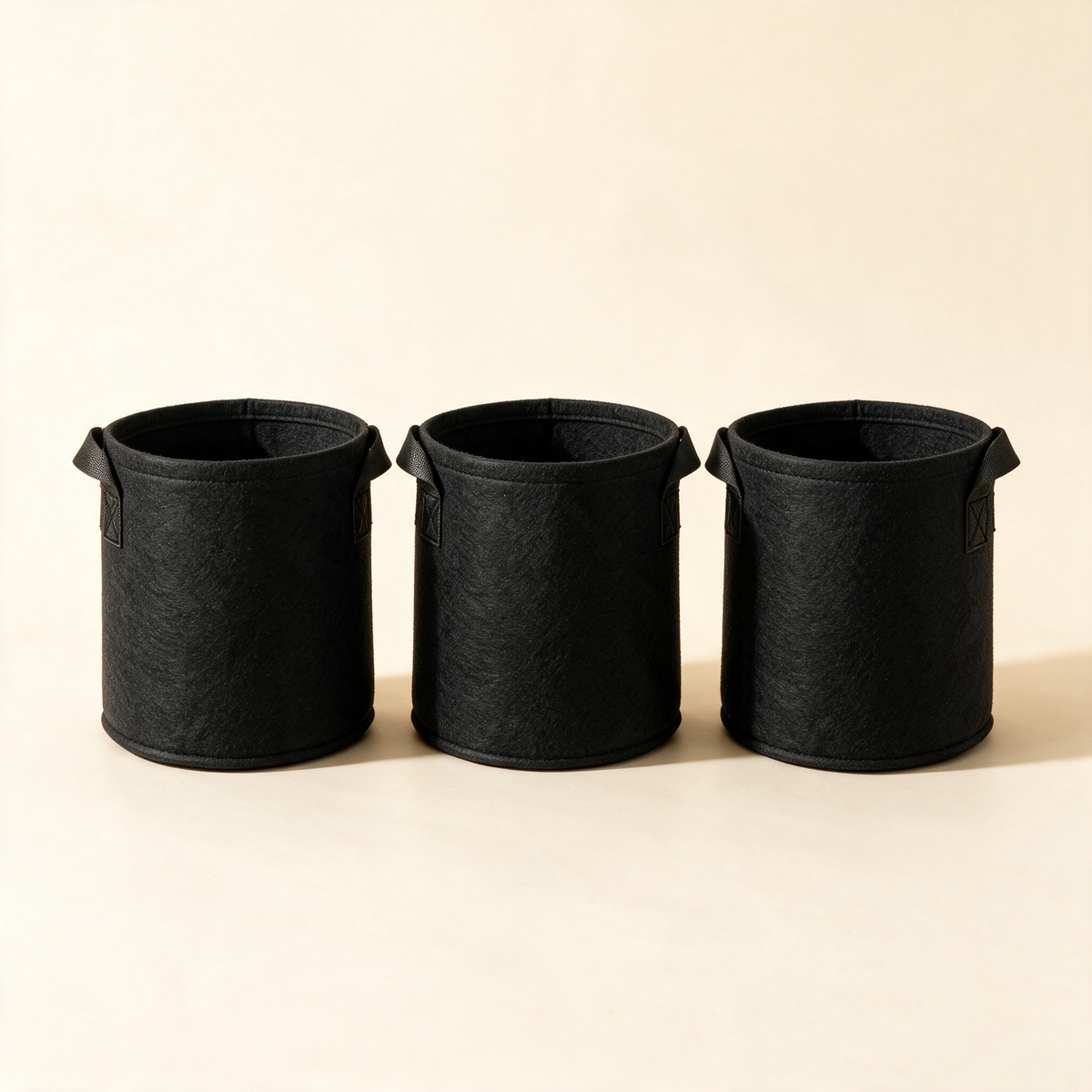 Set of three black fabric grow bags with handles for potted plants.