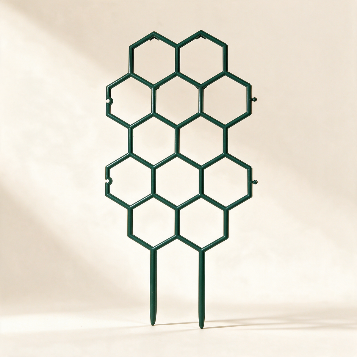 Green plastic honeycomb plant trellis stake with two ground spikes.